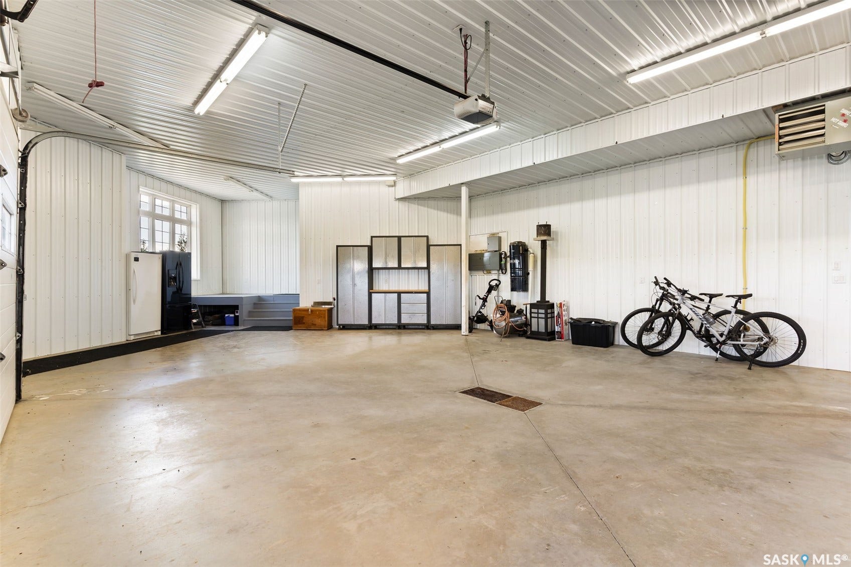Spacious garage with durable concrete flooring, overhead fluorescent lighting, and a white corrugated metal ceiling