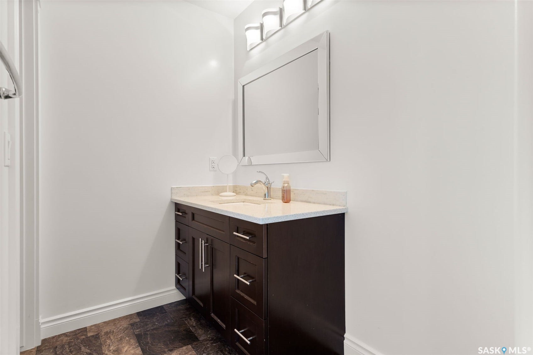 Dark wood-finish vanity with drawer storage, light-toned countertop, and integrated sink