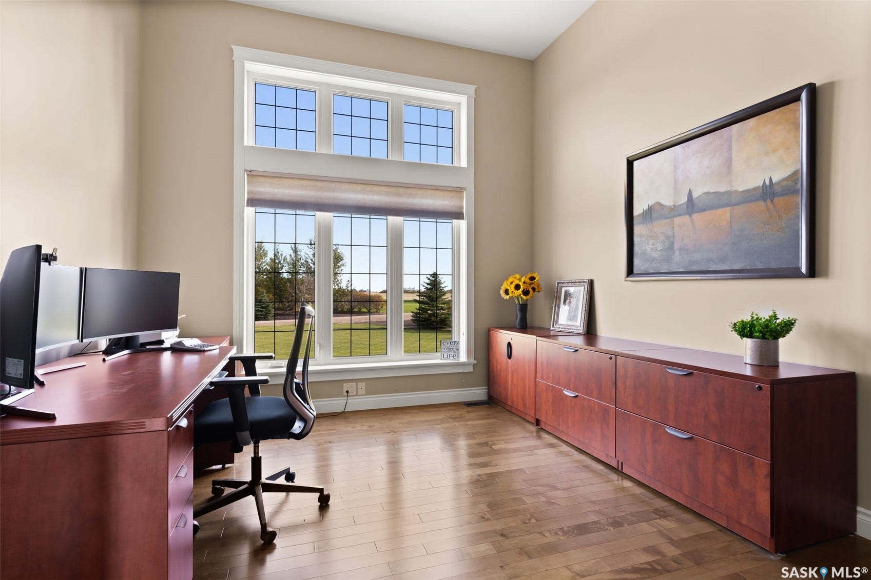 Vaulted ceiling, oversized windows, wood-finish flooring, built-in cabinetry, and neutral wall tones