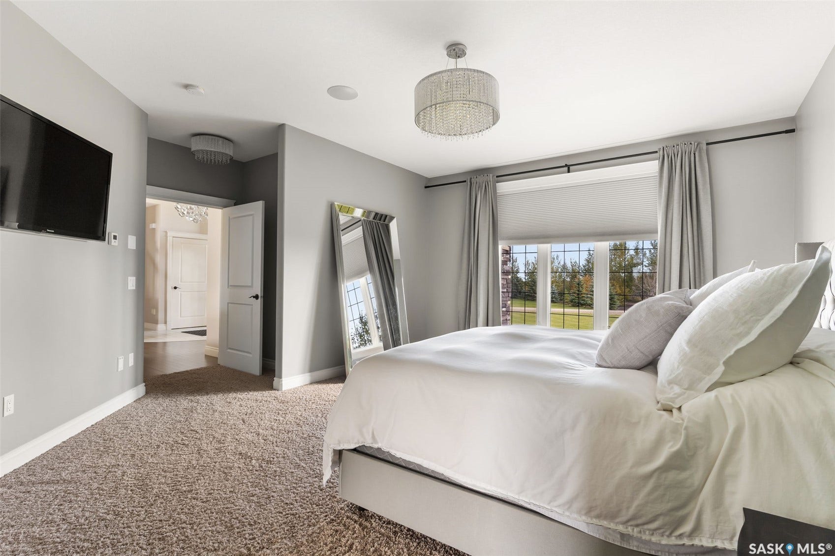 Recessed lighting, ceiling-mounted crystal chandelier, carpeted flooring, large window with roller shades, and paneled interior doors