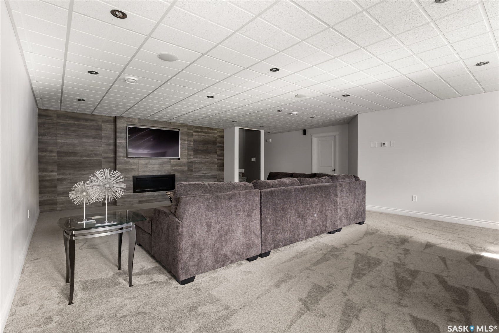 Recessed lighting, drop ceiling, wall-mounted electric fireplace, wood-look wall paneling, and wall-to-wall carpeting