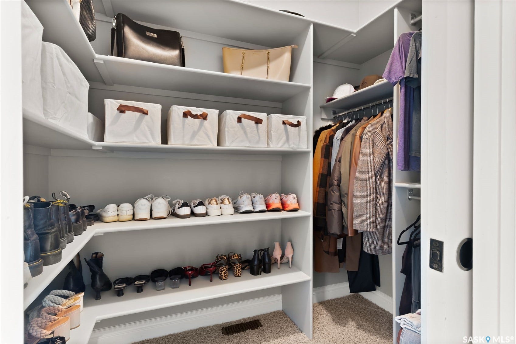 Walk-in closet with built-in shelving, multiple hanging rods, and pocket door entry