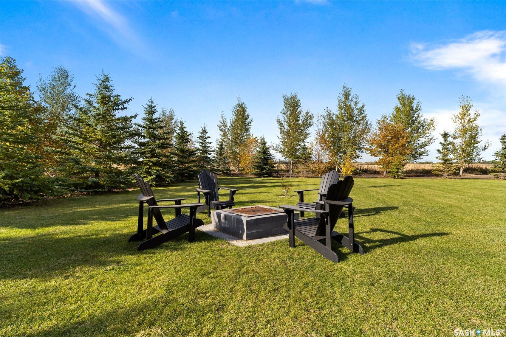 Expansive lawn featuring a concrete fire pit and mature trees