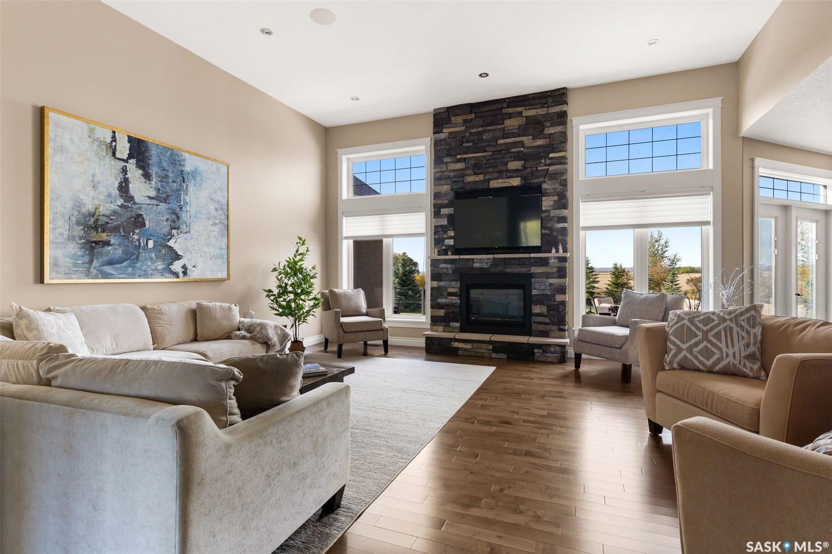 Vaulted ceilings, wood-finish flooring, stone-clad fireplace, built-in television, and transom windows