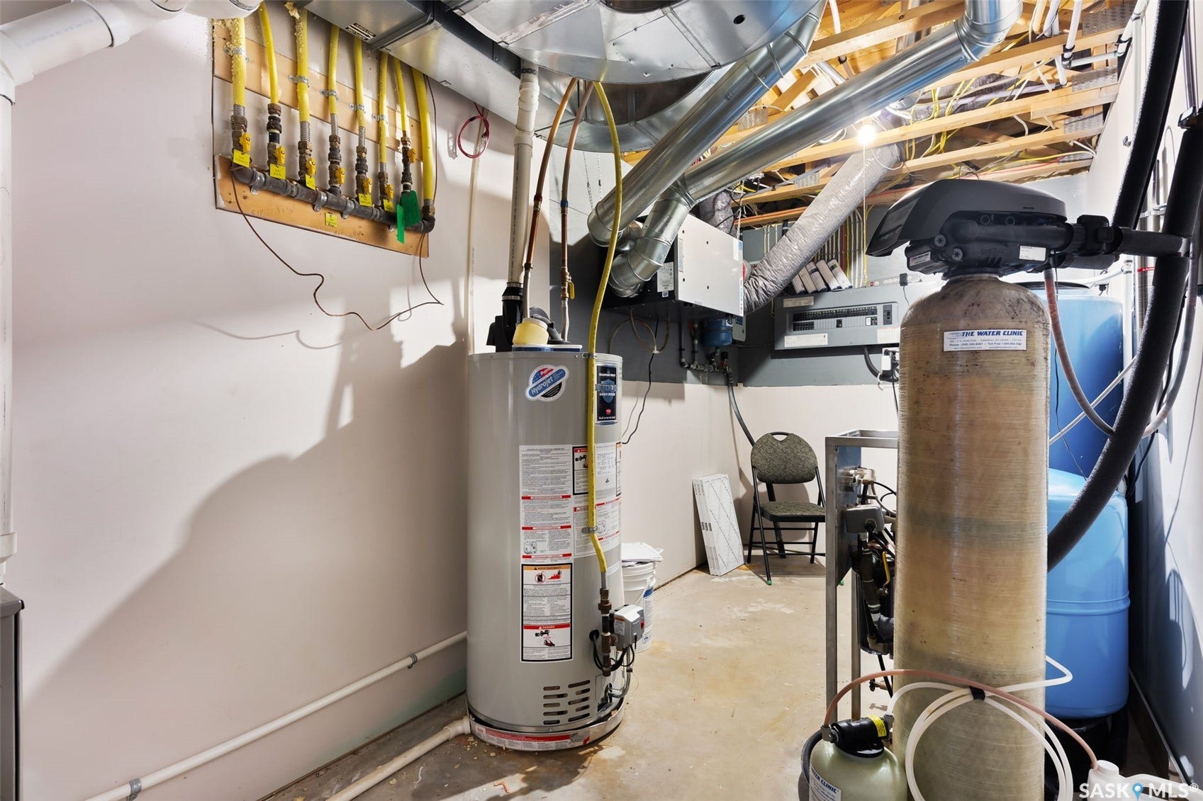Dedicated utility space featuring a water heater, water softener system, and exposed ceiling joists