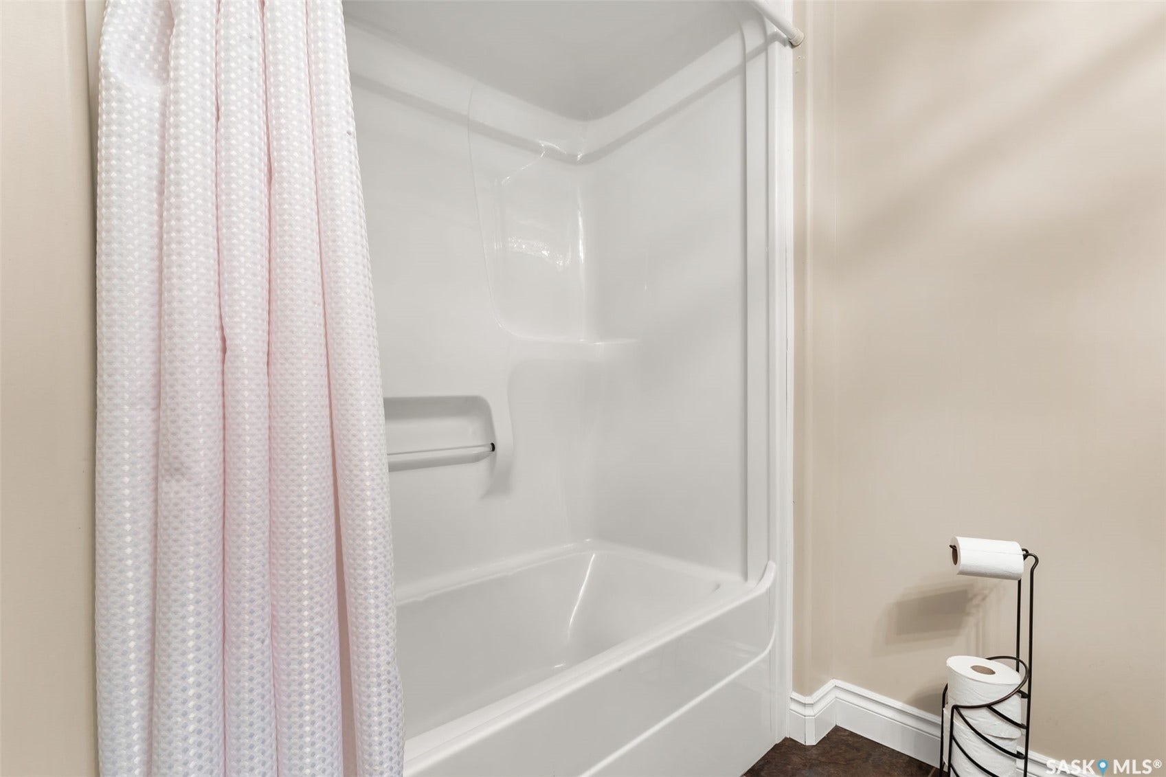 White fiberglass tub and shower combination with an integrated grab bar
