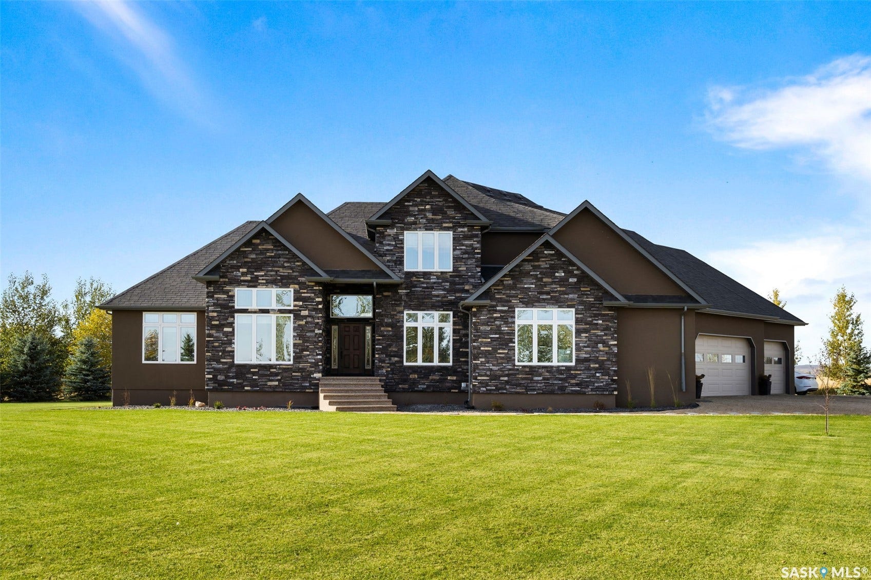 Stone and stucco exterior with dark shingle roofing