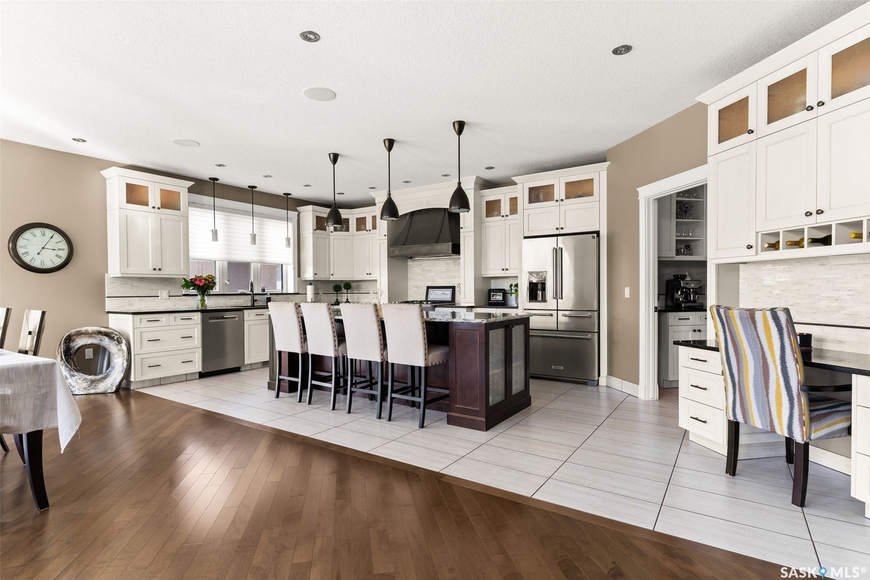 Kitchen featuring white cabinetry, a central island with seating, stainless steel appliances, and contrasting wood-finish flooring