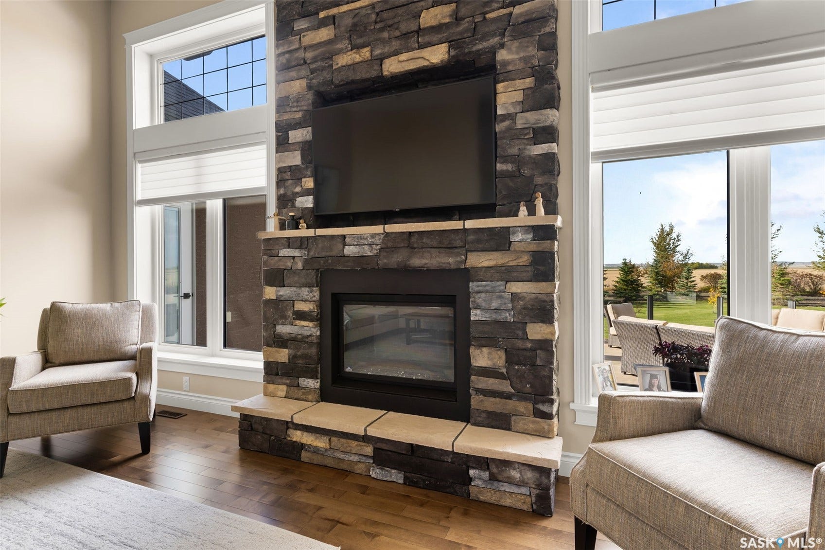 Stone-clad fireplace with hearth, wood-finish flooring, and expansive windows