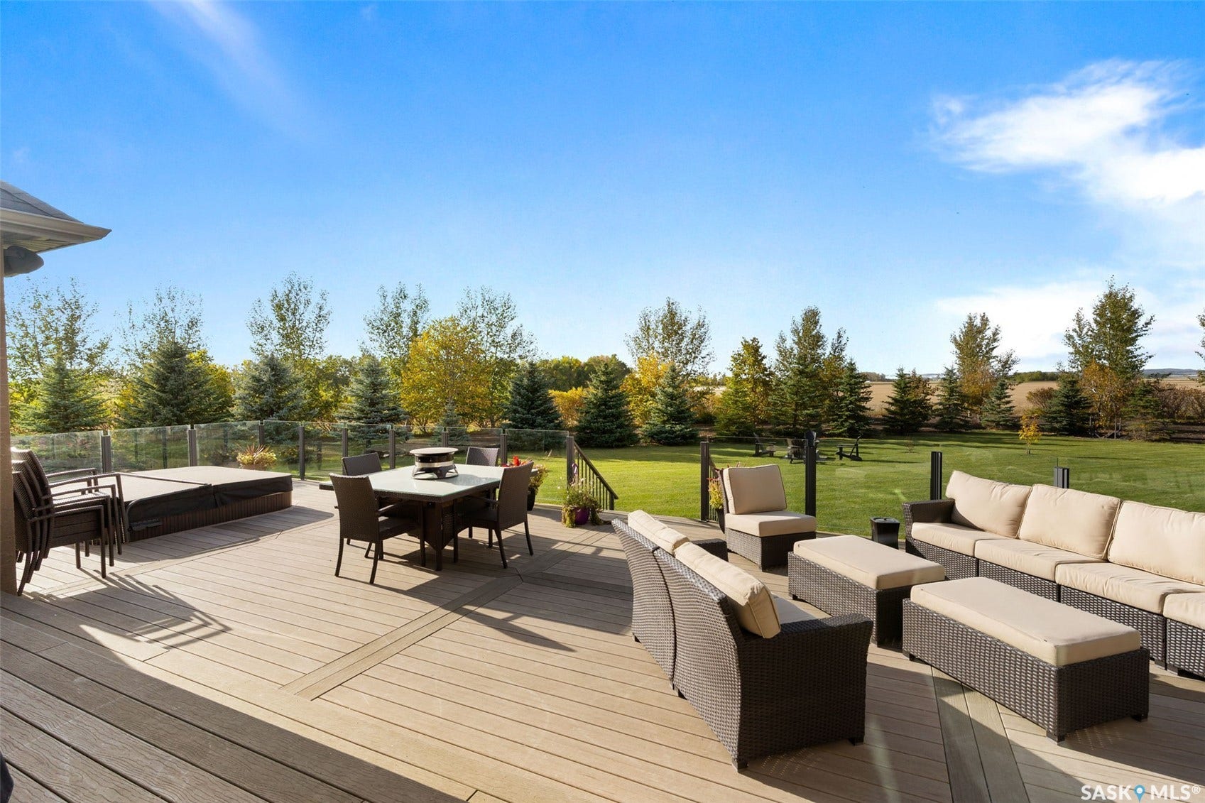Expansive outdoor deck featuring wood-finish decking, a built-in hot tub, and a clear panel railing system