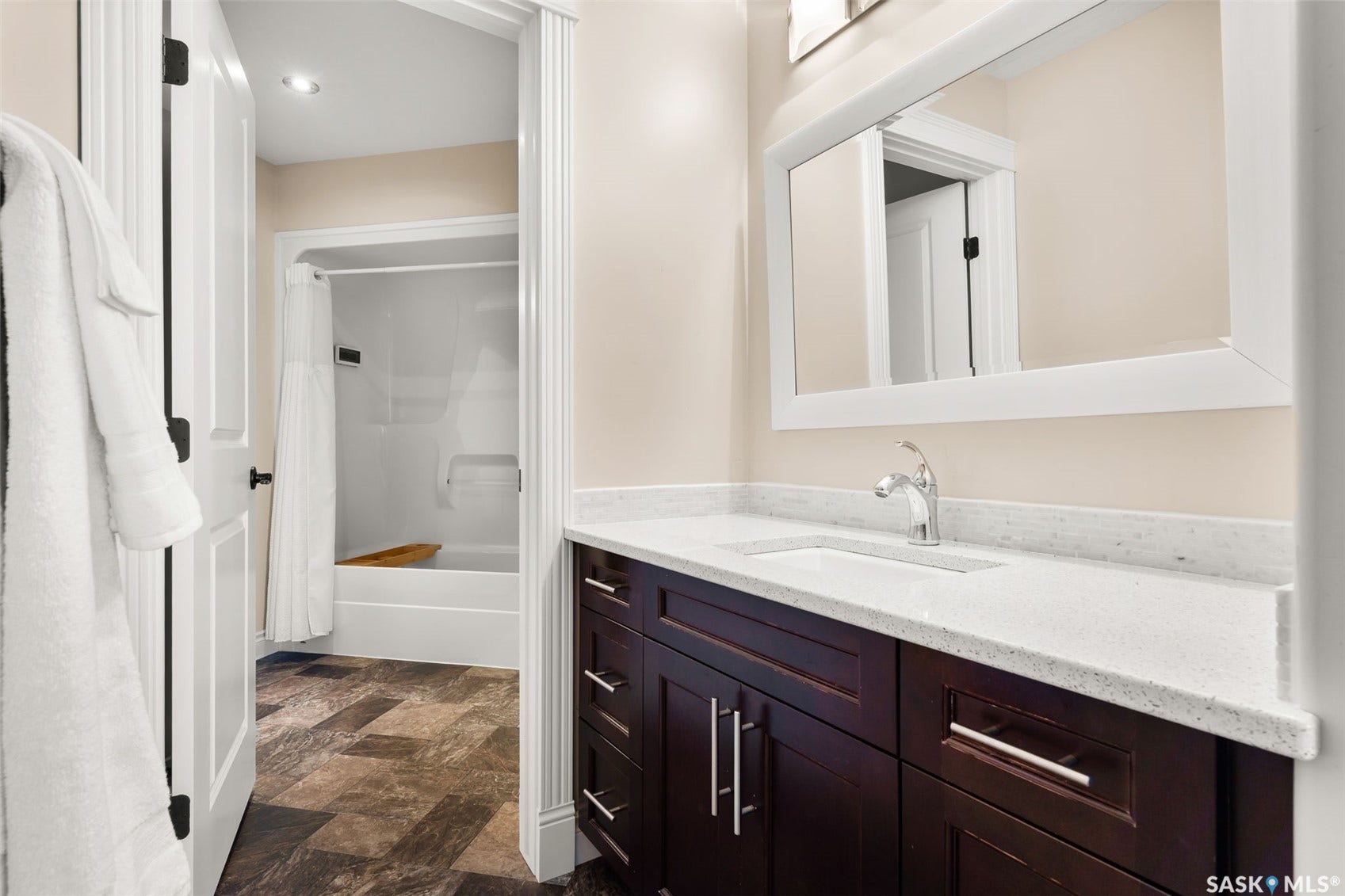 Dark wood-finish vanity with chrome hardware, white stone-finish countertop, and undermount sink
