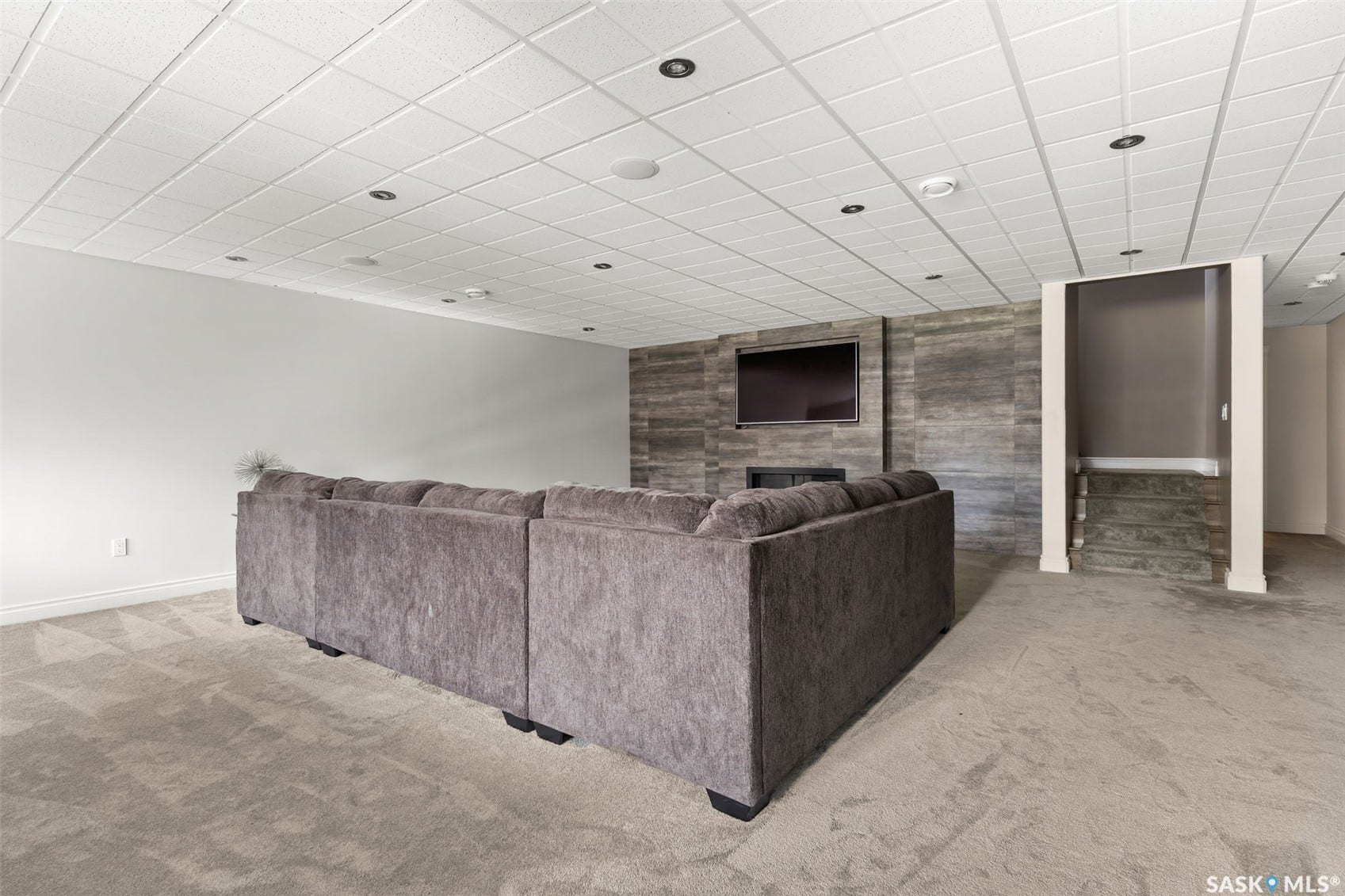 Recessed lighting, wood-finish accent wall, built-in fireplace, drop ceiling, and carpeted flooring