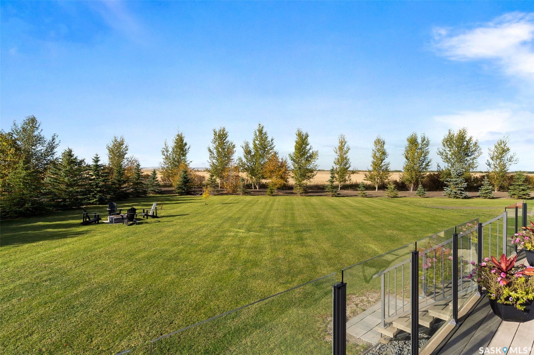 Expansive backyard featuring a manicured lawn, established trees, and a ground-level fire pit area