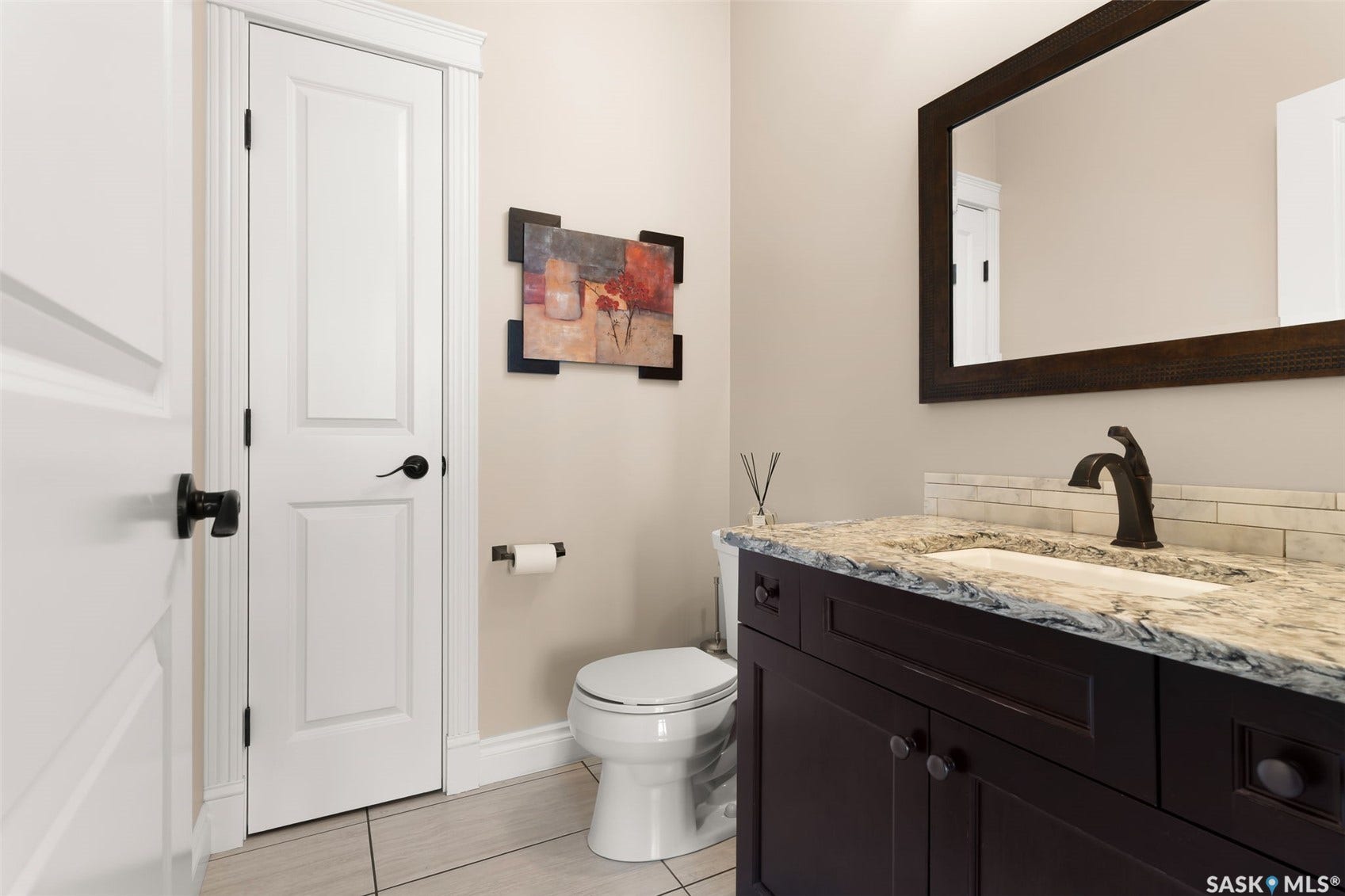Dark wood-finish vanity with an undermount sink, granite countertop, and bronze-finish faucet