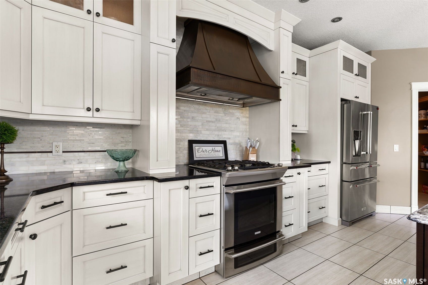 White shaker-style cabinetry with dark hardware, stainless steel appliances, dark countertops, and a full tile backsplash