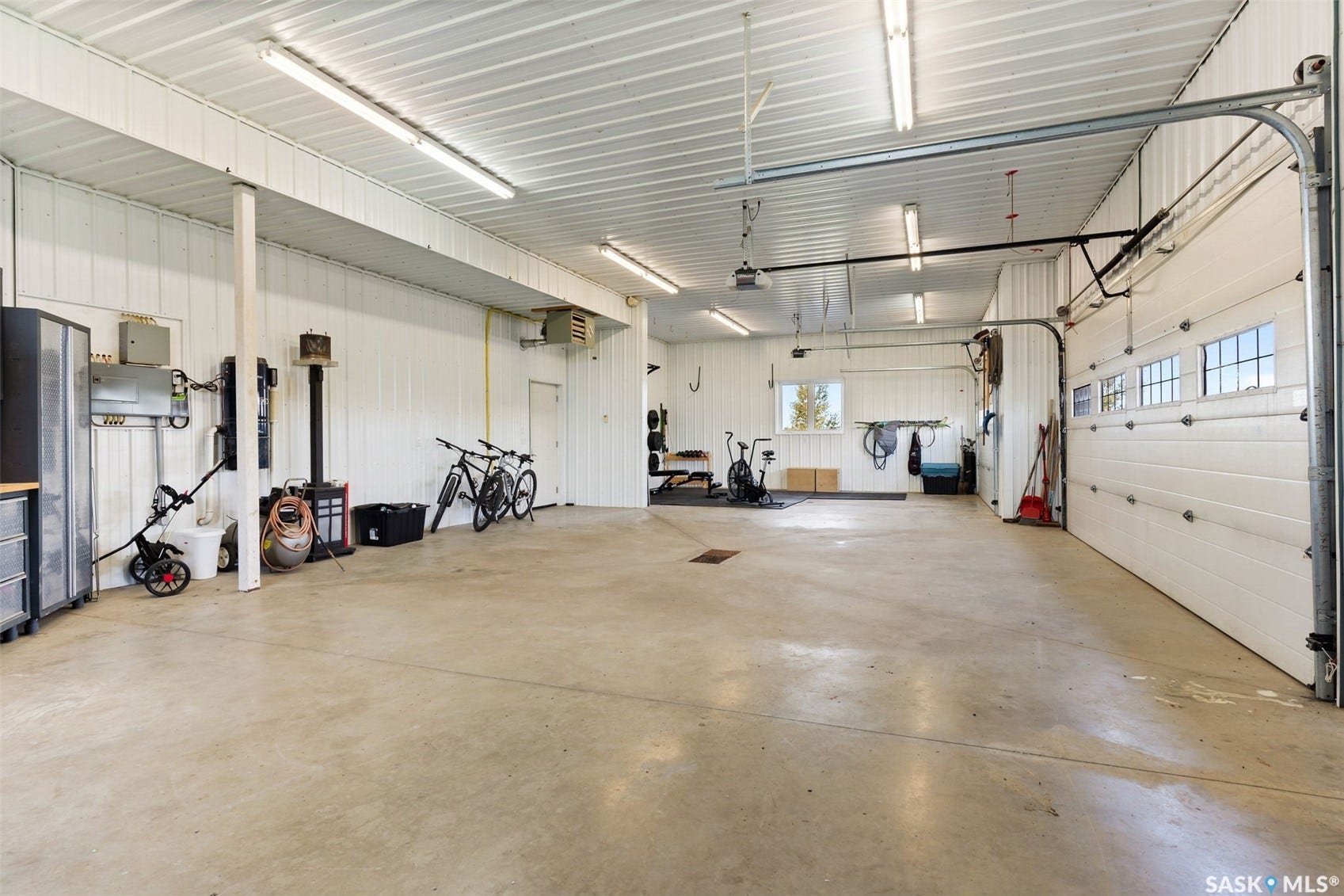 Spacious garage with multiple overhead doors, concrete flooring, and ample overhead lighting