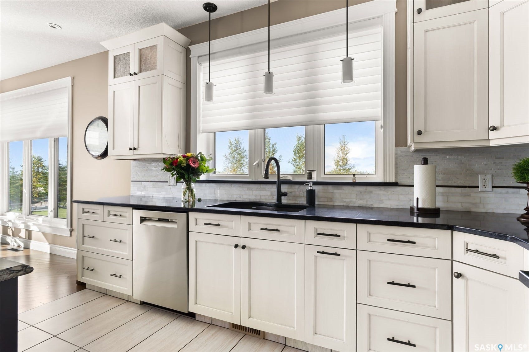White shaker-style cabinetry with dark hardware, dark countertops, tile backsplash, and wood-finish flooring