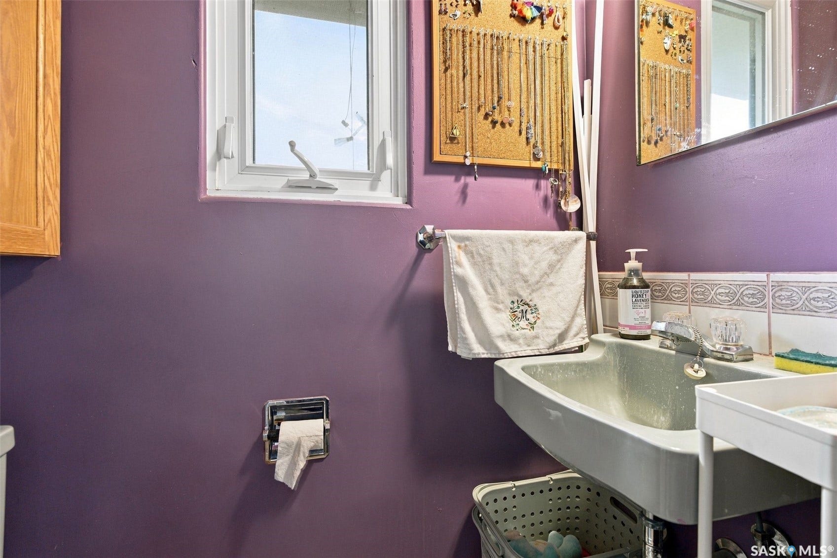 Wall-mounted sink with stainless steel faucet, white tiled backsplash, and natural wood-finish cabinetry