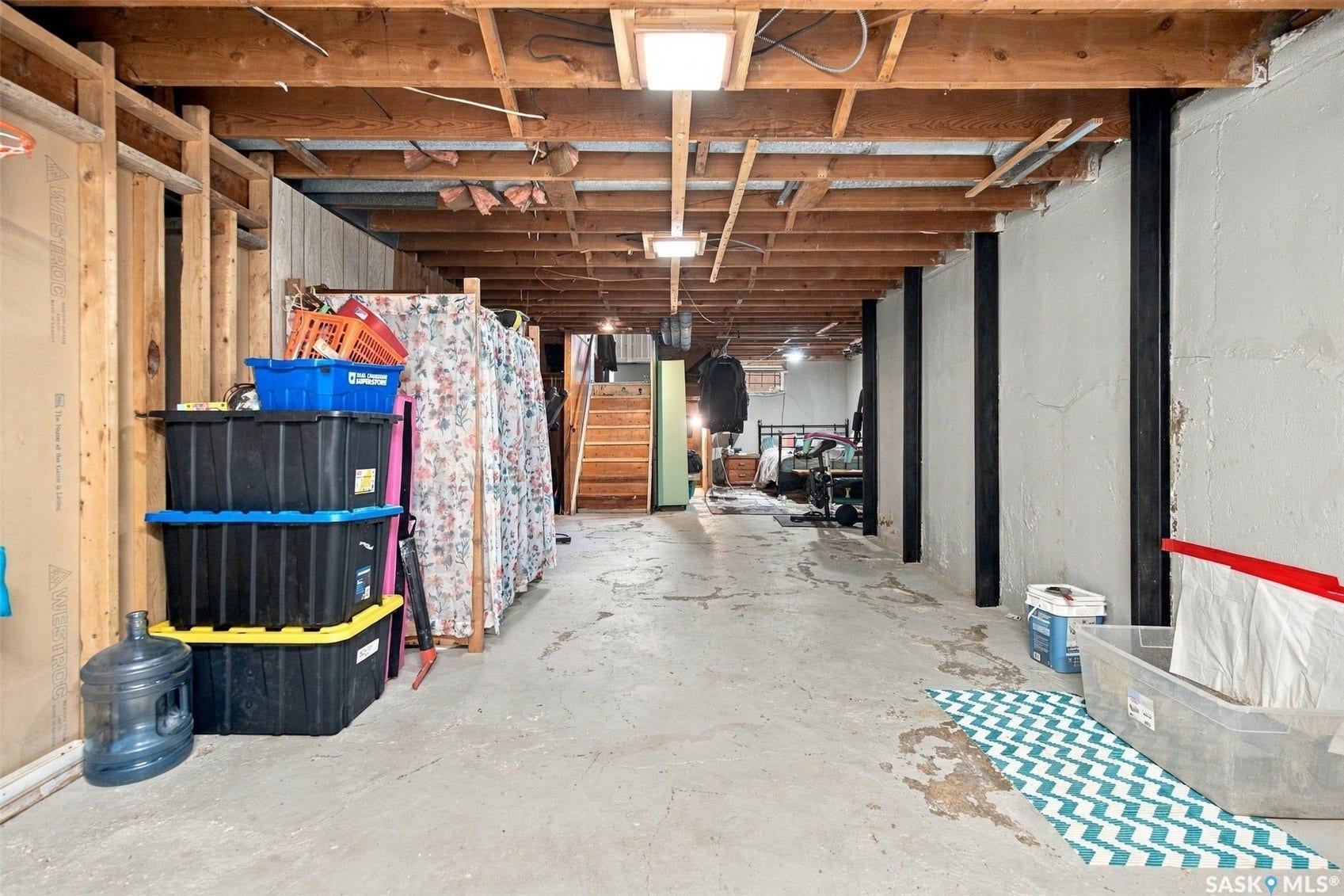 Concrete flooring, exposed wood ceiling beams, structural support columns, recessed lighting