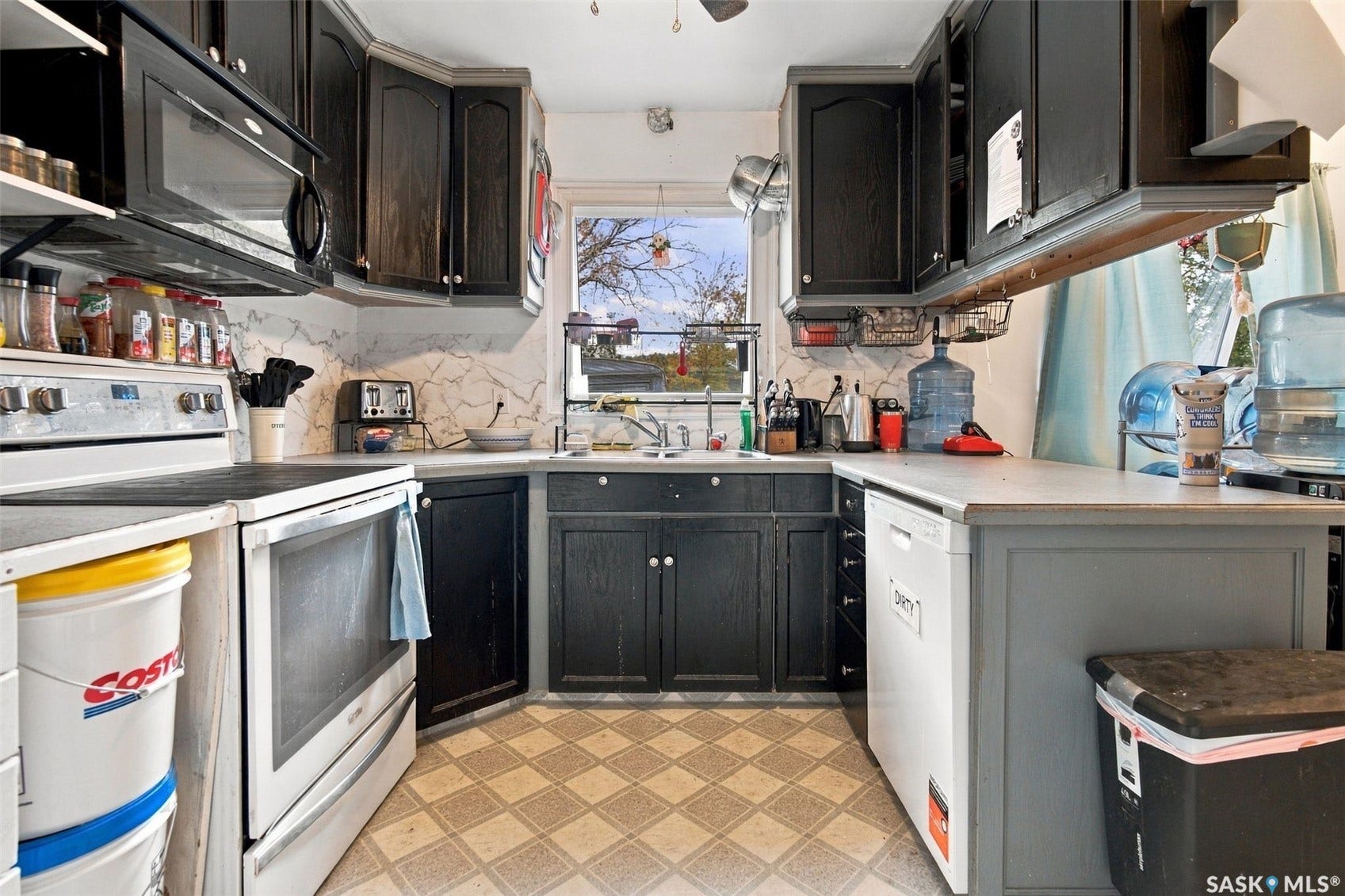 Kitchen featuring dark cabinetry, white countertops, tile-patterned flooring, a stainless steel range, and an over-the-range microwave