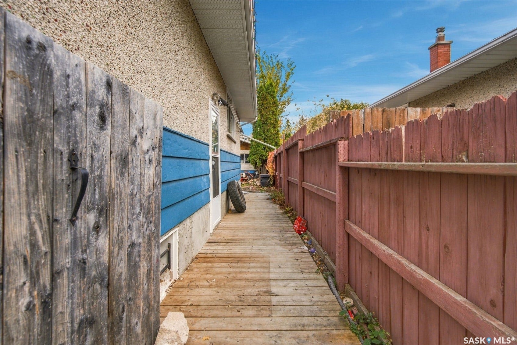Wood plank walkway with a stained wood fence and stucco exterior