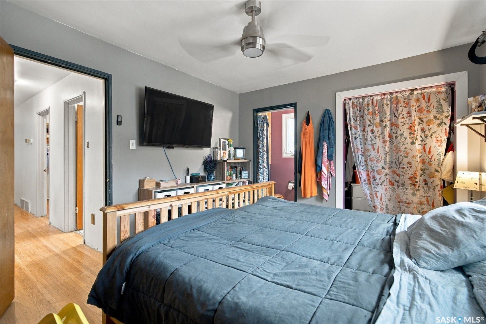 Light wood-finish flooring, ceiling fan fixture, and wall-mounted television bracket
