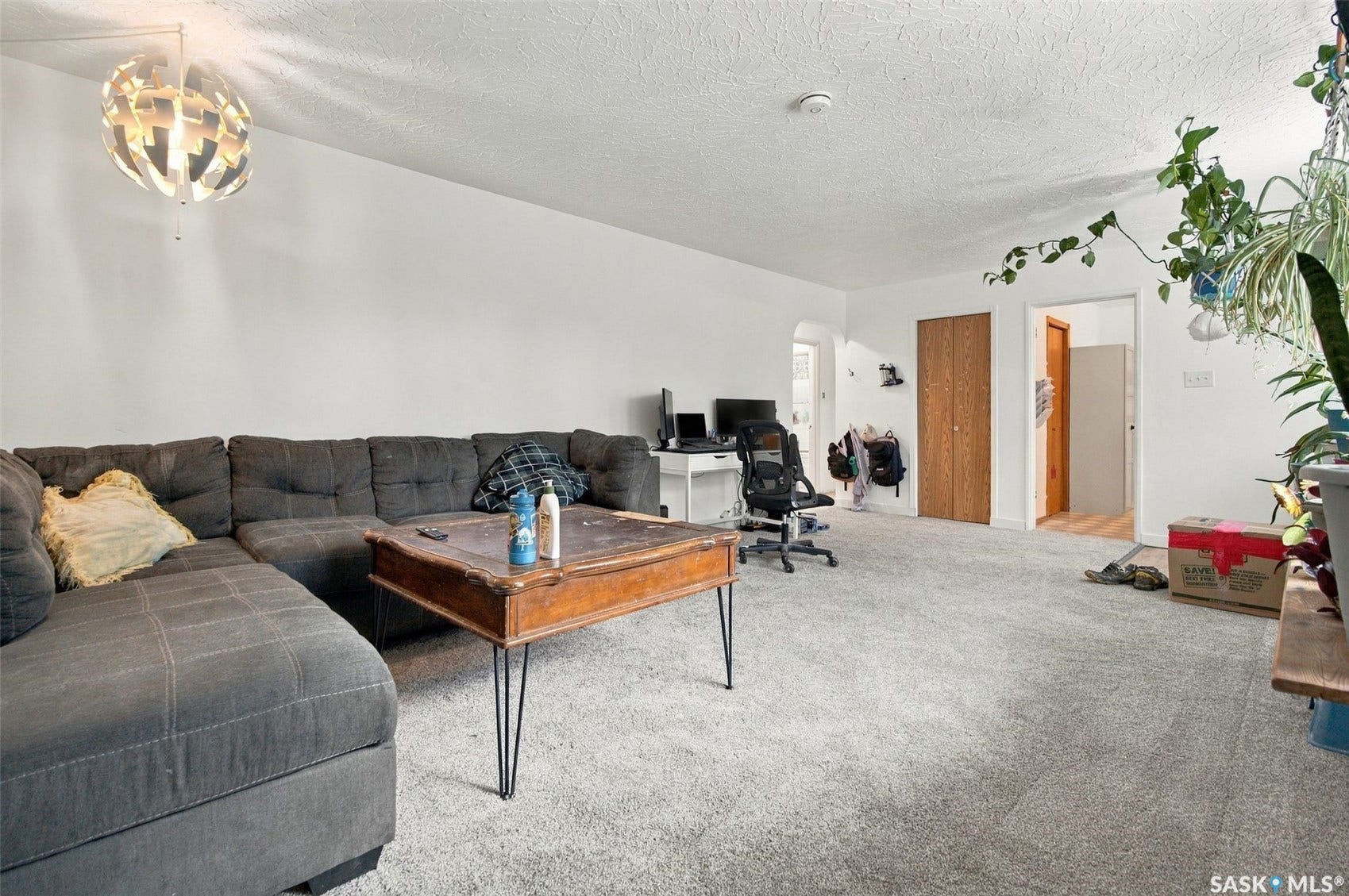 Carpeted living space with white walls and a contemporary pendant light fixture