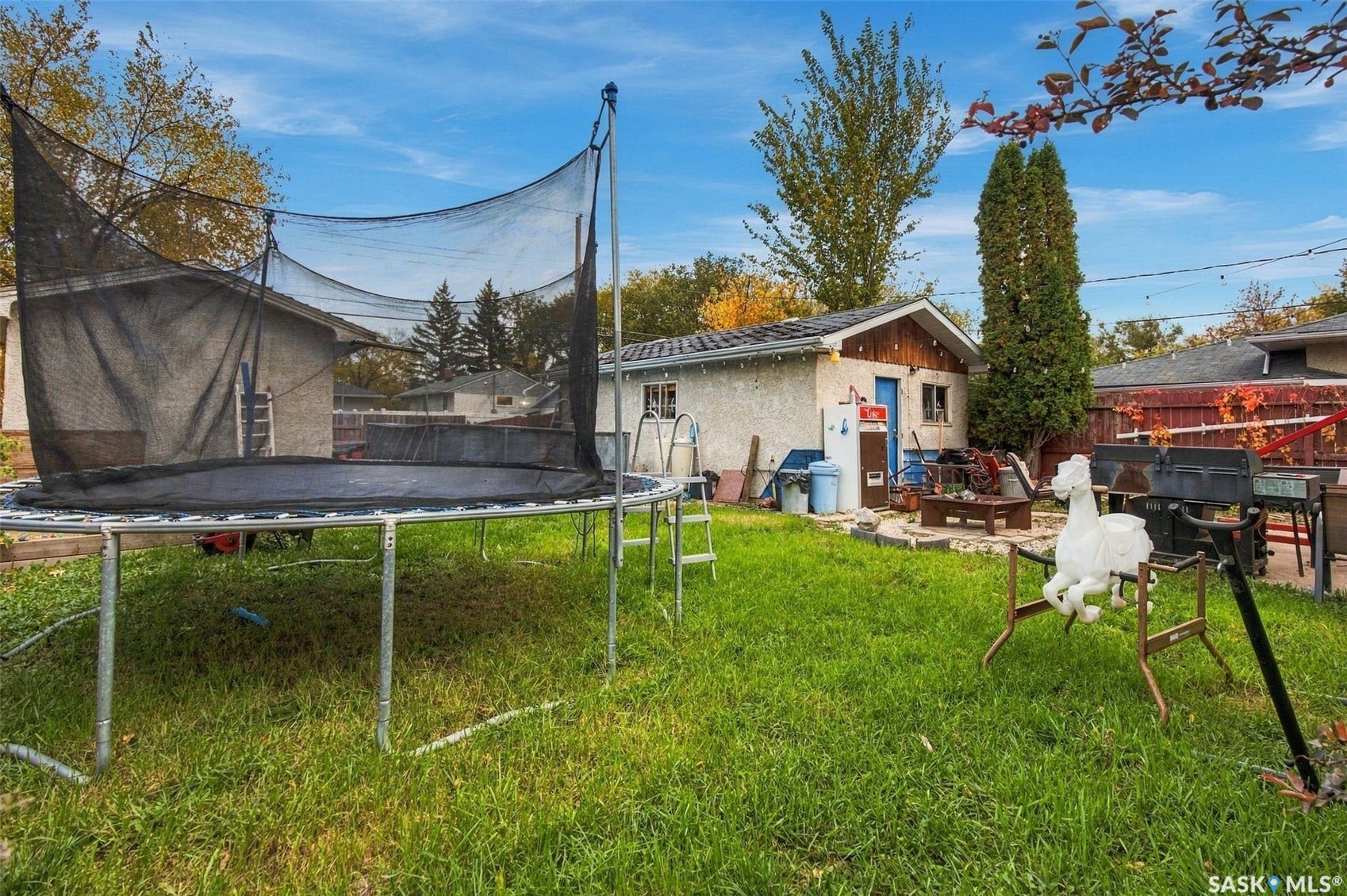 Spacious backyard with mature landscaping, lush lawn, and established trees