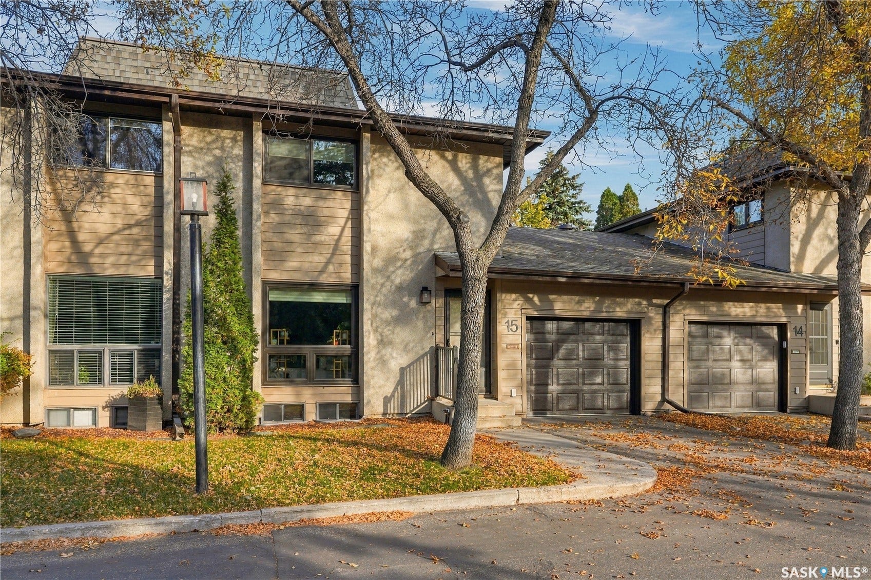 Two-story stucco and wood-finish exterior with multiple windows and attached garages