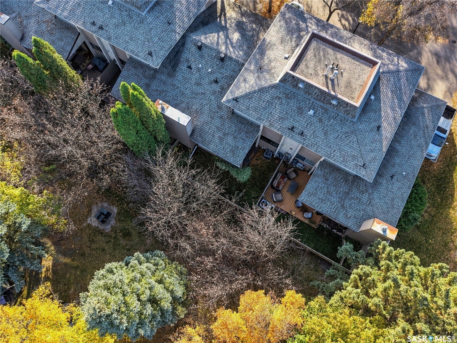Rear exterior with multi-level roofing, a flat roof section, and a ground-level deck