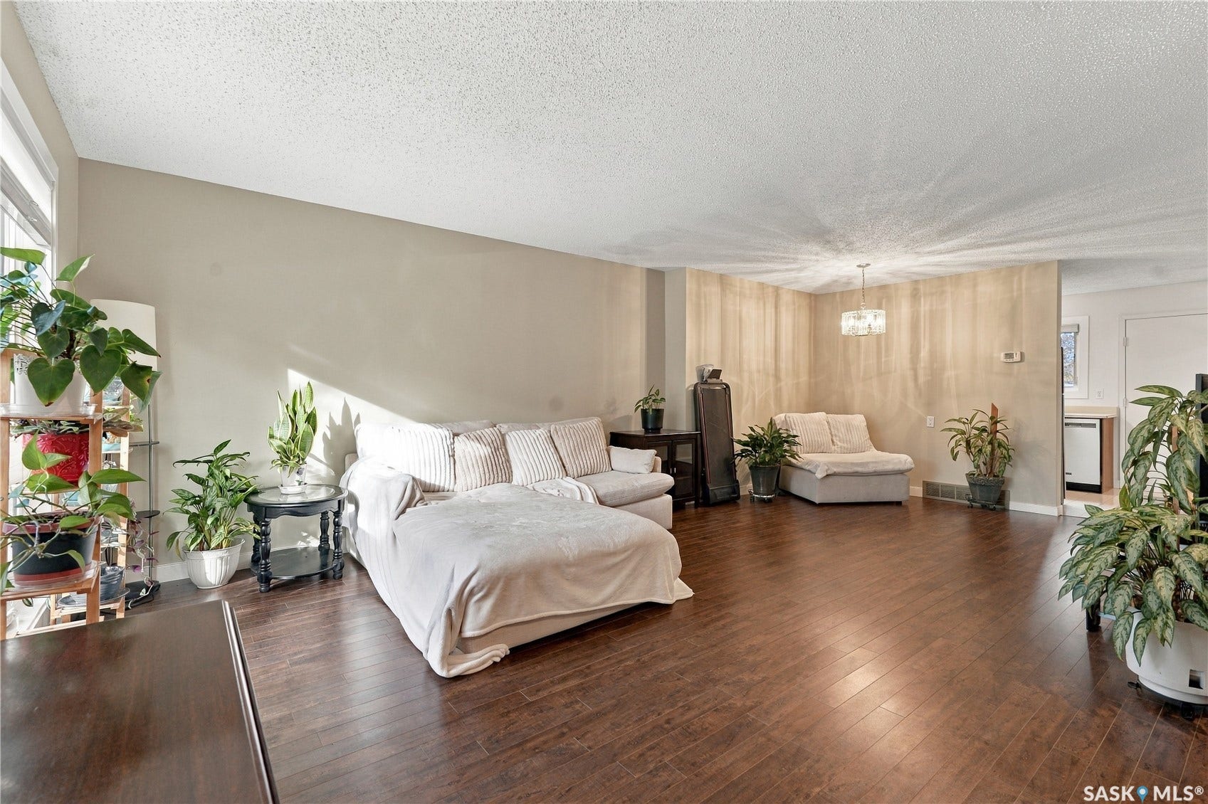 Expansive living area featuring rich wood-finish flooring, neutral wall tones, and a prominent window providing natural light