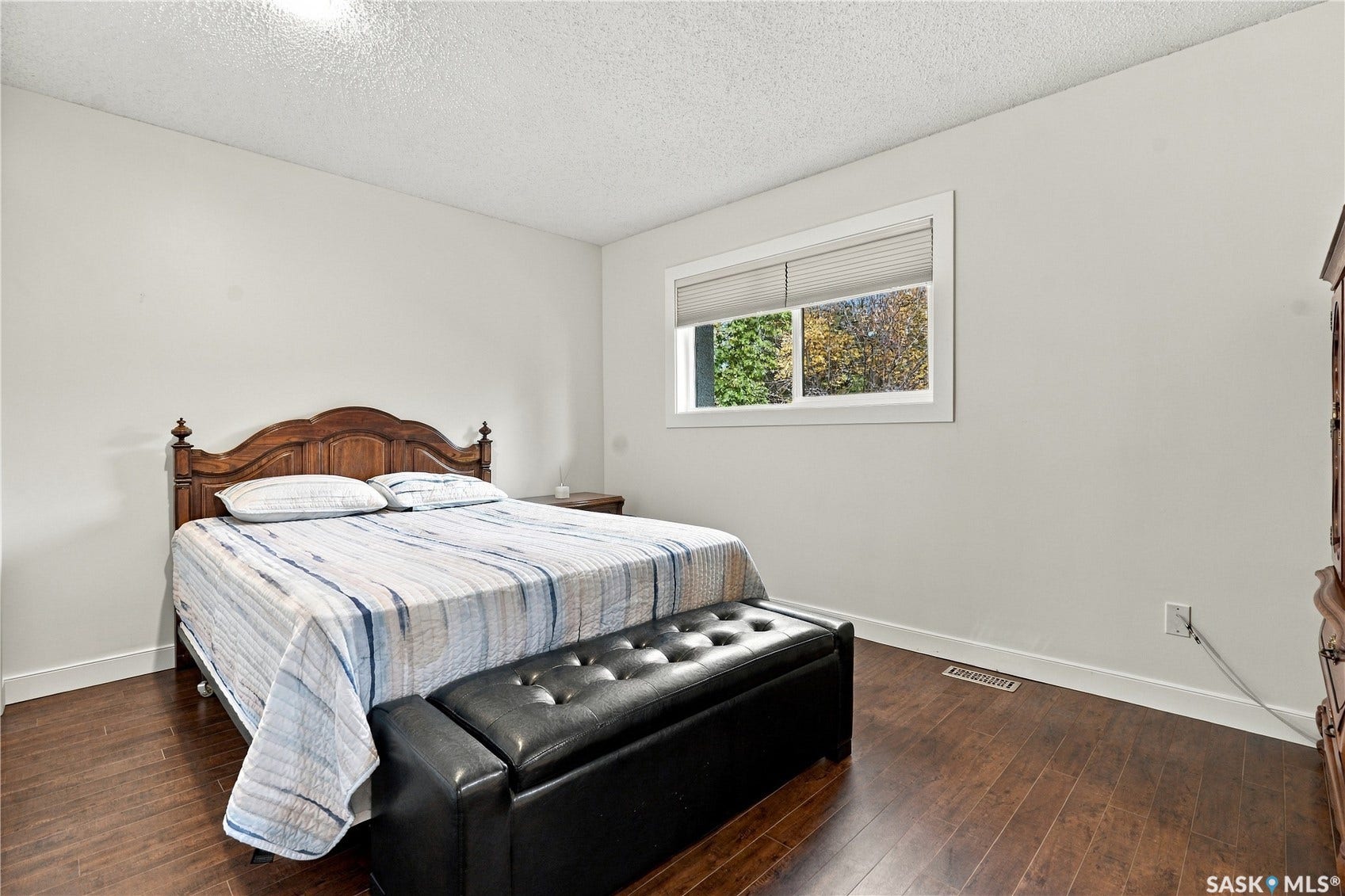 Room featuring wood-finish flooring, a window with blinds, and white walls