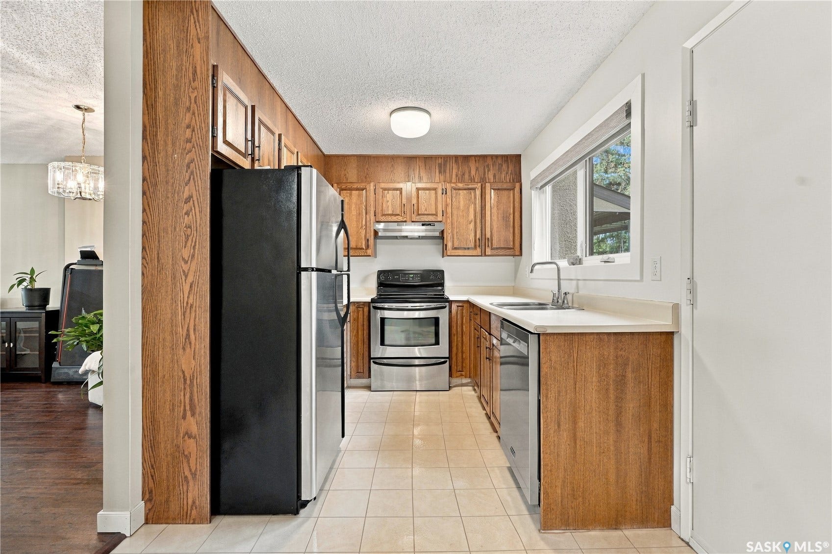 Kitchen with wood-finish cabinetry, stainless steel appliances, and a window above the sink