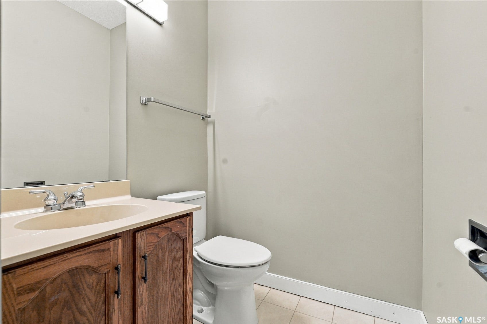 Wood-finish cabinetry with dark hardware, integrated sink and countertop, chrome faucet, and overhead vanity lighting