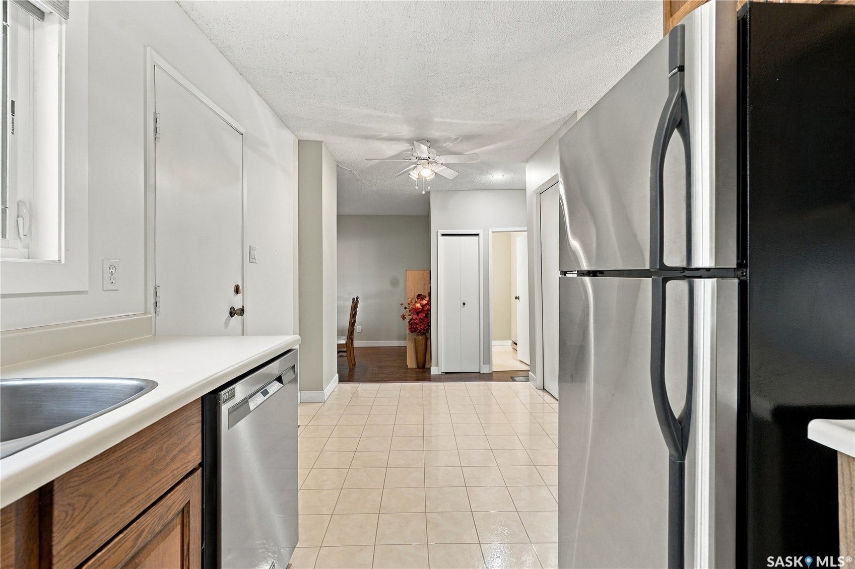 Kitchen featuring tile flooring, wood-finish cabinetry, stainless steel dishwasher, stainless steel refrigerator, and ceiling fan