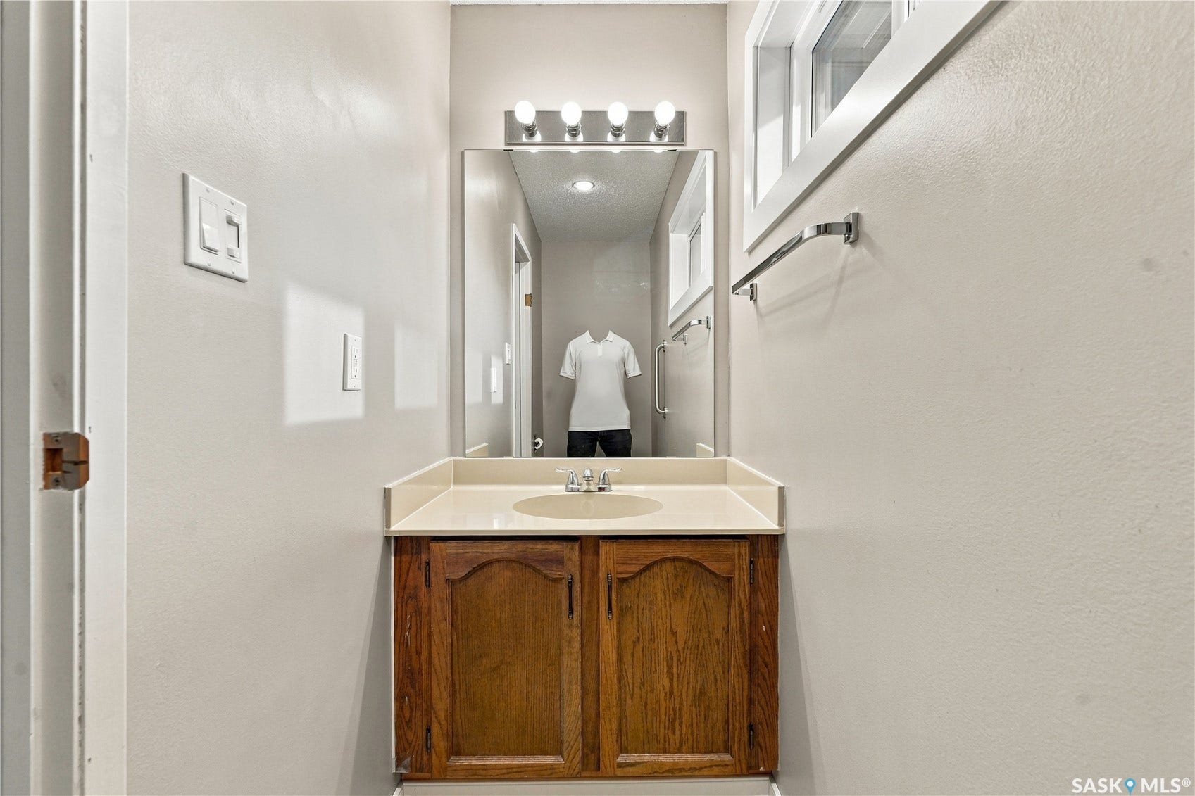 Vanity with wood-finish cabinetry, integrated sink, and light-toned countertop