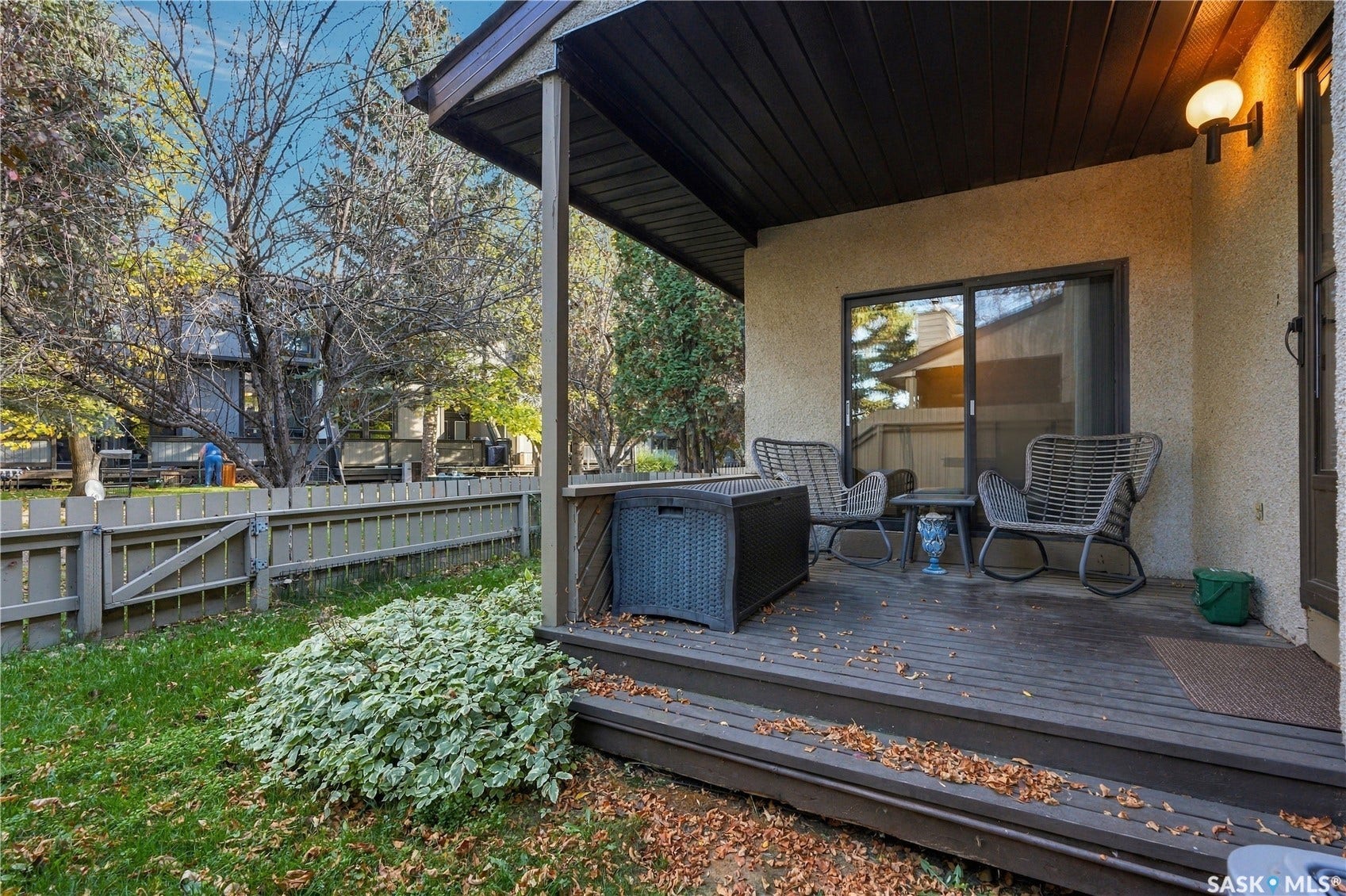 Covered outdoor patio with wood-finish decking, stucco exterior, and sliding glass door access