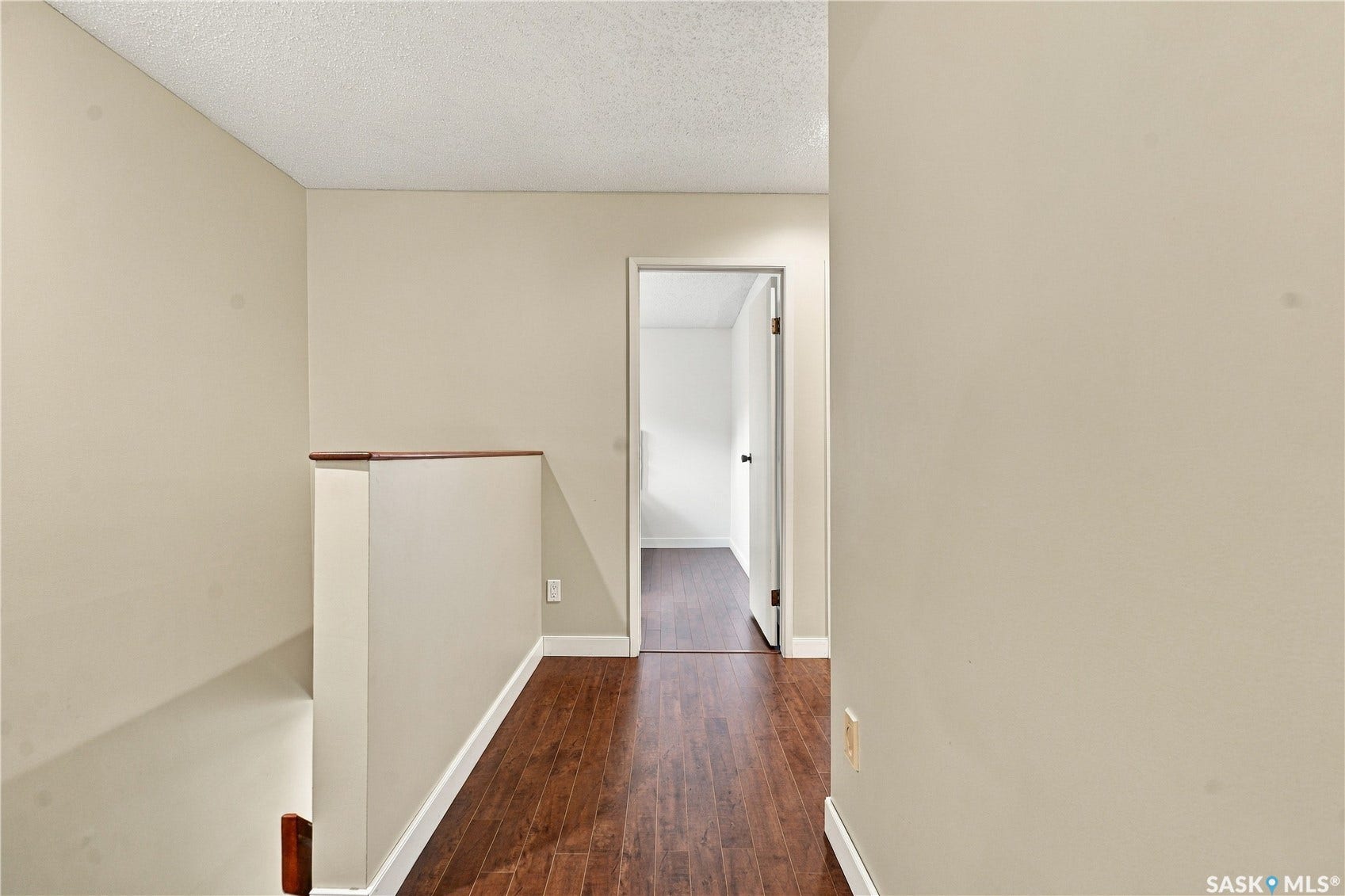 Wood-finish flooring, light-toned wall finishes, interior door with dark hardware, and white trim