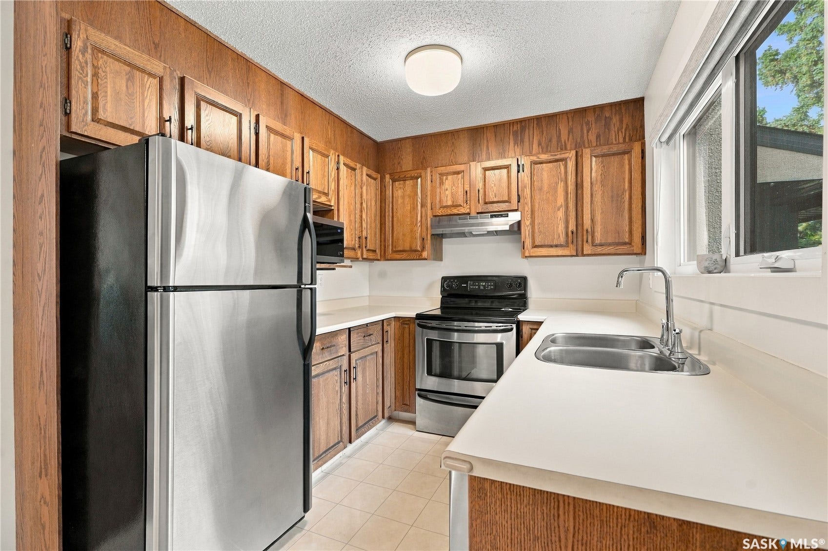 Kitchen featuring wood cabinetry, stainless steel appliances, white countertops, and a double basin sink