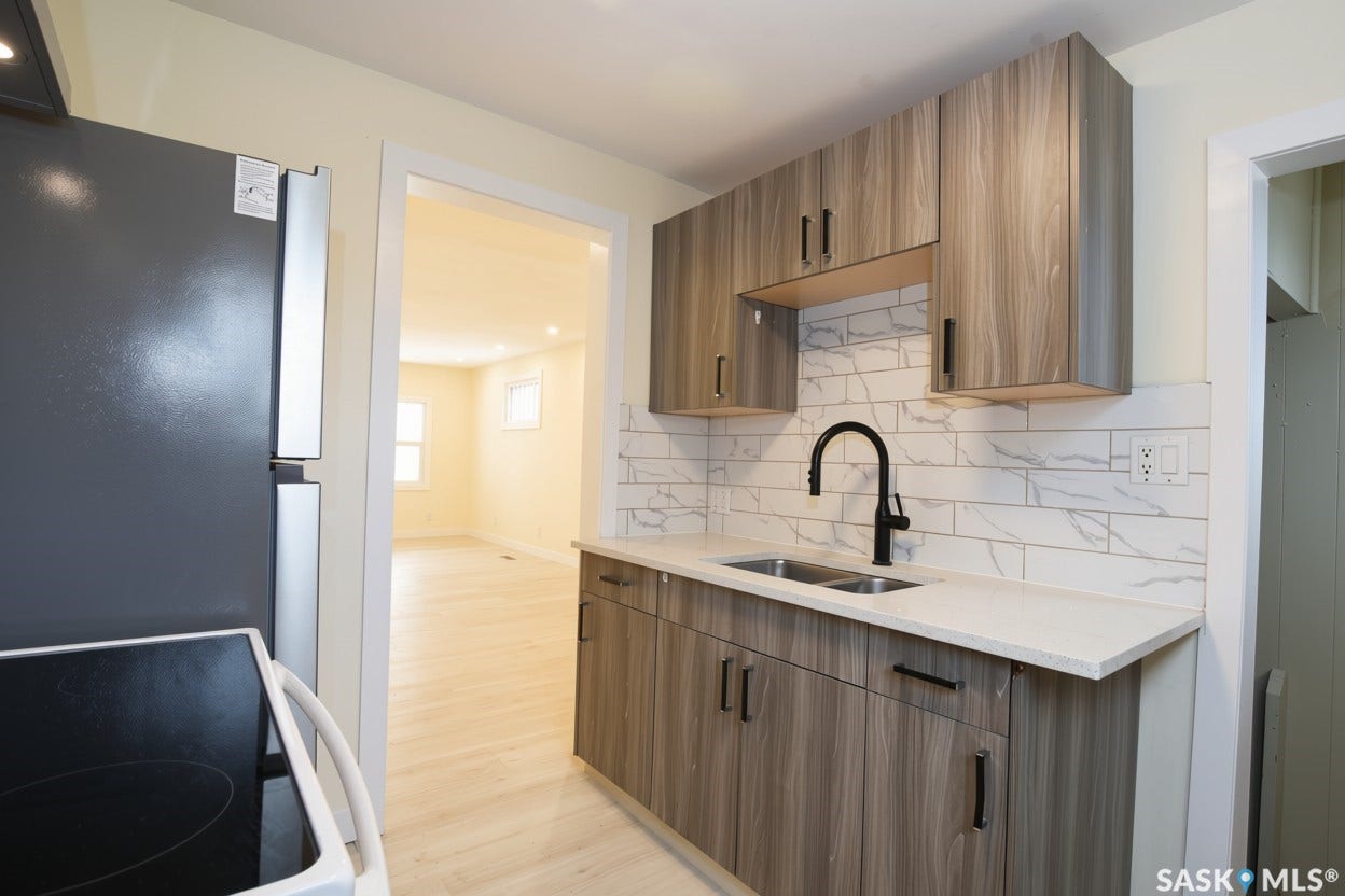 New stainless steel double basin sink with a matte black faucet. New quartz counter top, new cabinets and tile backsplash