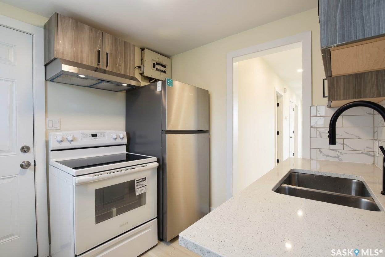Kitchen featuring a new stainless steel refrigerator and a new white electric stove , and light-toned upper cabinetry, and a range hood