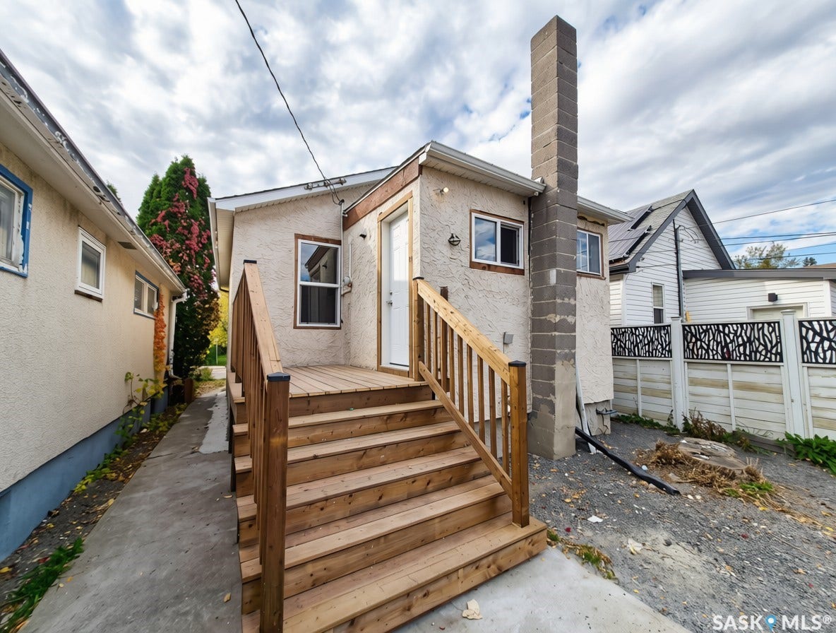 Rear exterior featuring a new wood-plank deck, wood staircase with railings, and stucco siding