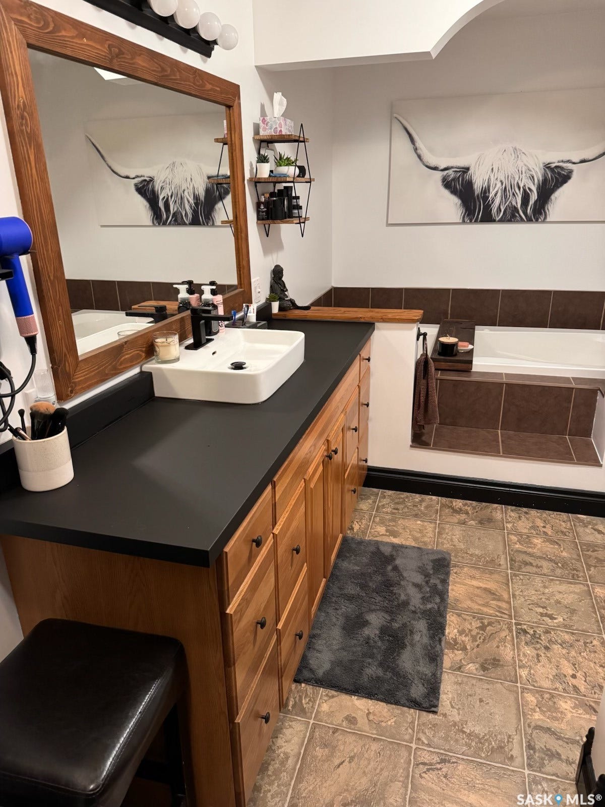 Wood-finish vanity with a dark countertop, an undermount rectangular vessel sink, and a wall-mounted faucet