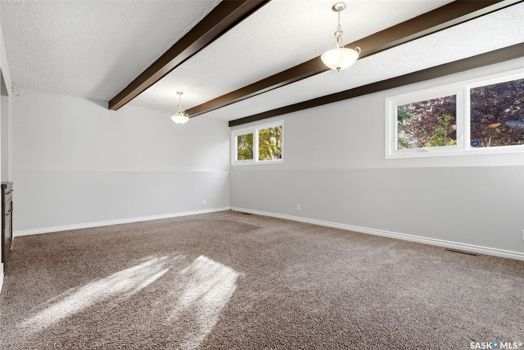 3361 Wascana Street, Regina SK S4S 2H2 Vaulted ceiling with exposed wood beams, neutral carpeting, light-toned walls, and multiple windows