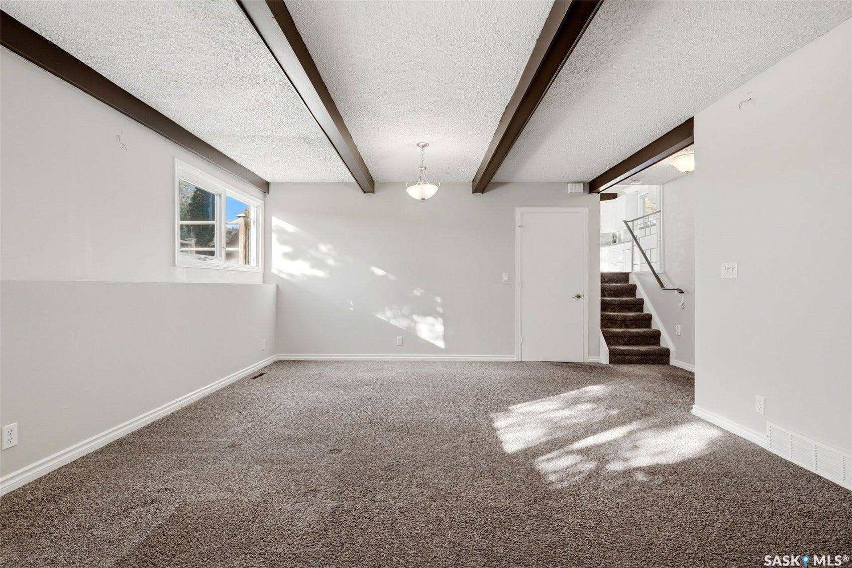 3361 Wascana Street, Regina SK S4S 2H2 Carpeted room featuring exposed ceiling beams, a window, and an overhead light fixture