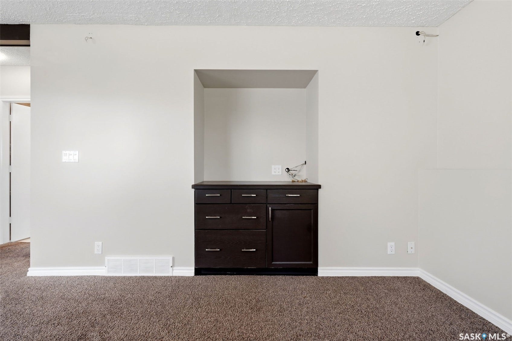 3361 Wascana Street, Regina SK S4S 2H2 Built-in dark wood cabinetry with silver hardware, integrated wall niche, and neutral wall paint