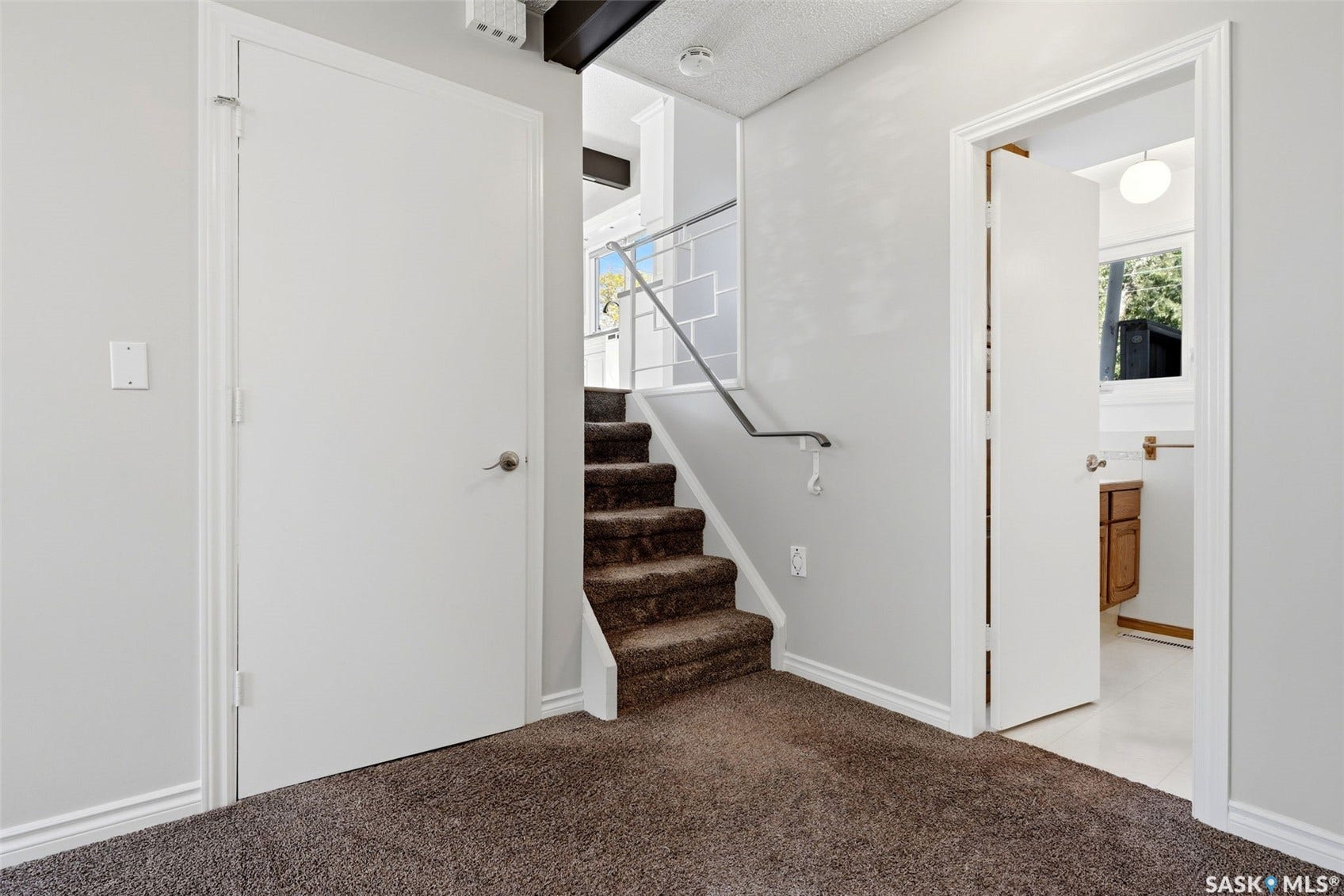 3361 Wascana Street, Regina SK S4S 2H2 Carpeted staircase with a metal handrail, light gray wall finishes, and white trim
