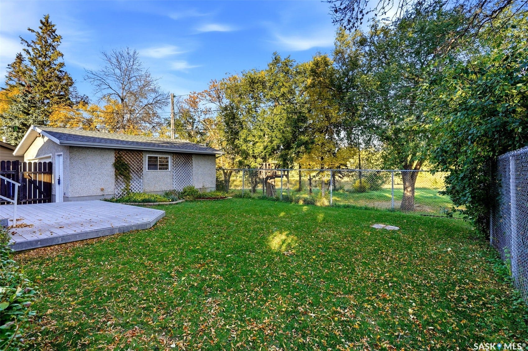 3361 Wascana Street, Regina SK S4S 2H2 Expansive green lawn with mature trees and a chain-link fence