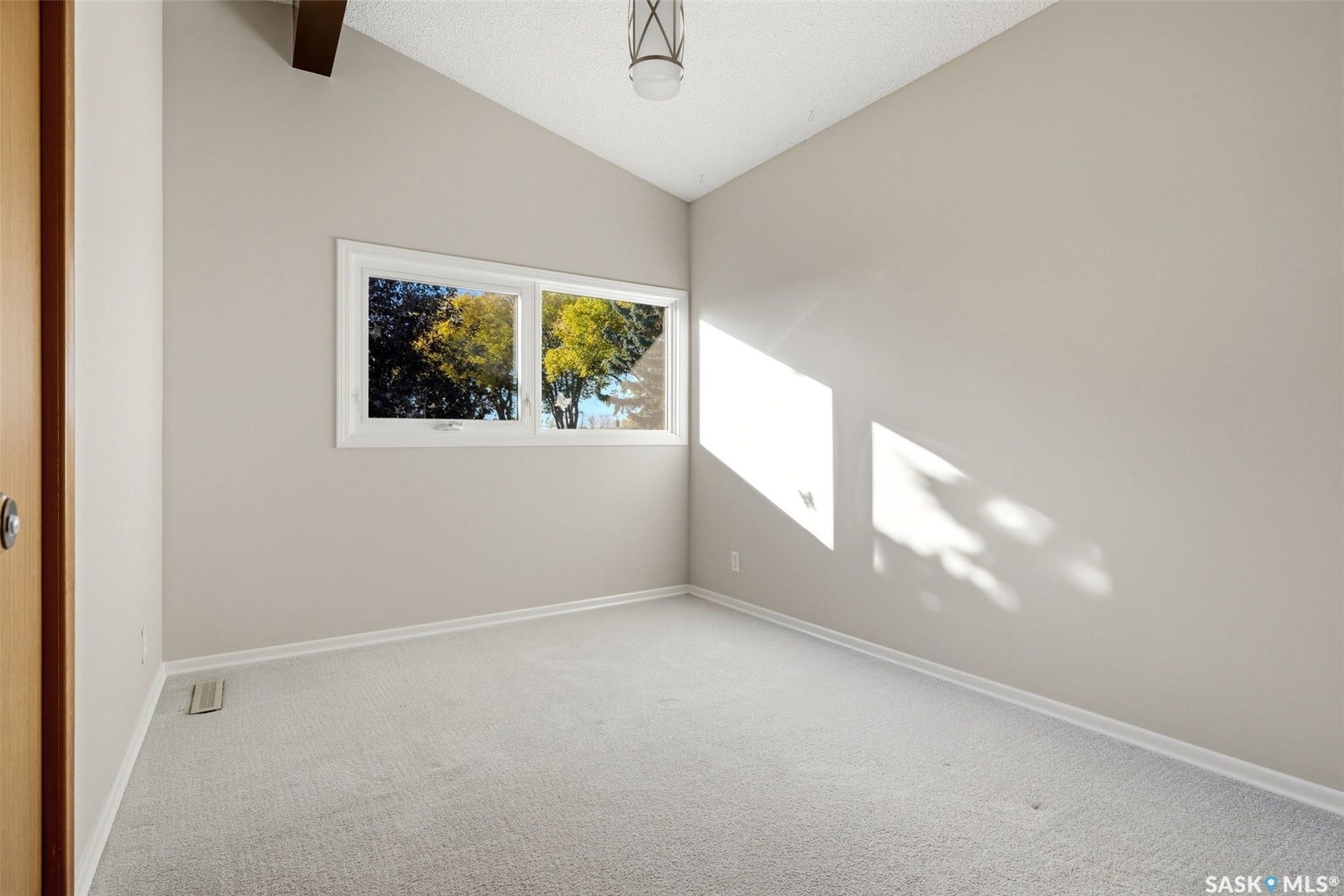 3361 Wascana Street, Regina SK S4S 2H2 Vaulted ceiling with exposed beam, window with exterior scenery, light-toned carpeting, and a flush-mount ceiling light fixture