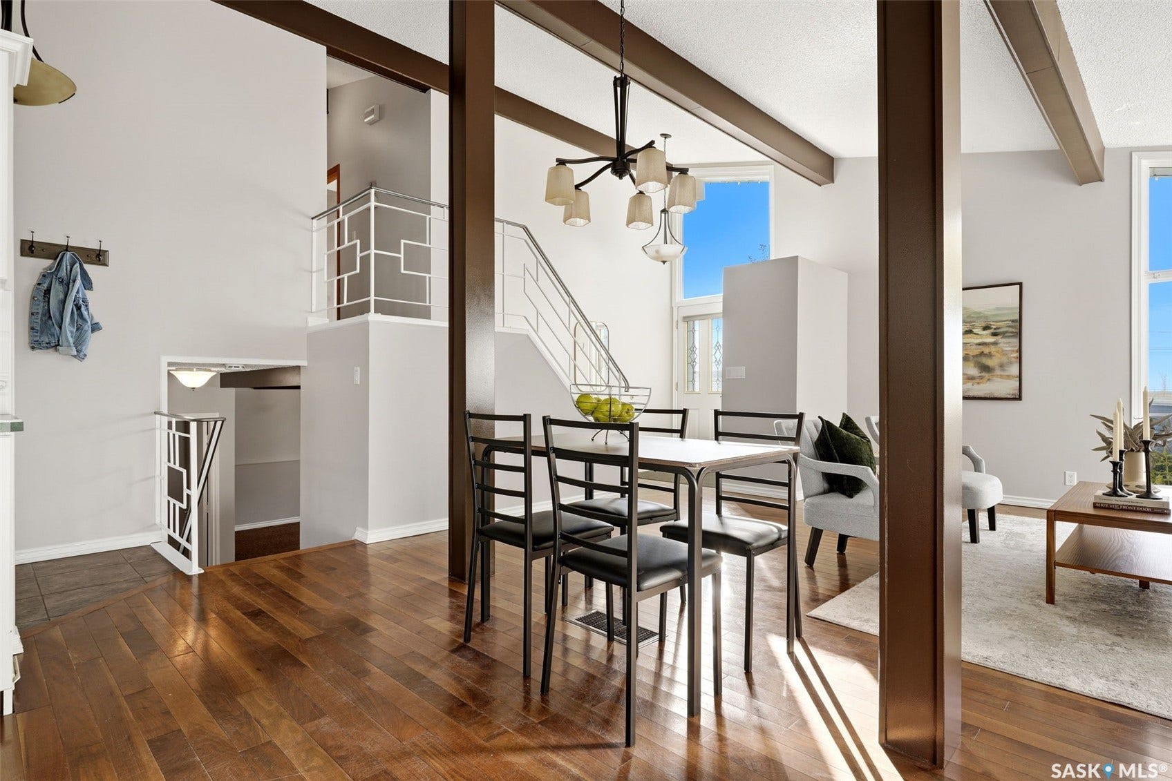 3361 Wascana Street, Regina SK S4S 2H2 Hardwood flooring throughout, exposed ceiling beams, modern chandelier, multiple windows, and a contemporary railing on a multi-level staircase
